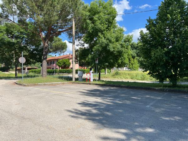 St. Archangel parking lot with white stripes, bordered by trees, near quiet residential area.